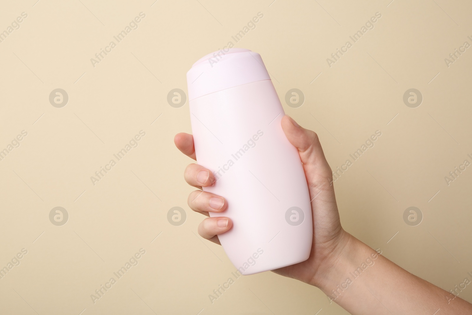 Photo of Woman with shampoo bottle on beige background, closeup