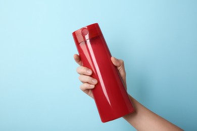 Photo of Woman with shampoo bottle on light blue background, closeup