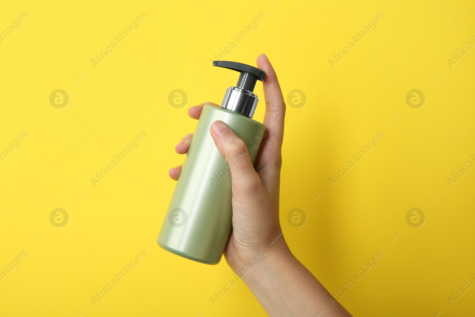 Photo of Woman with shampoo bottle on yellow background, closeup