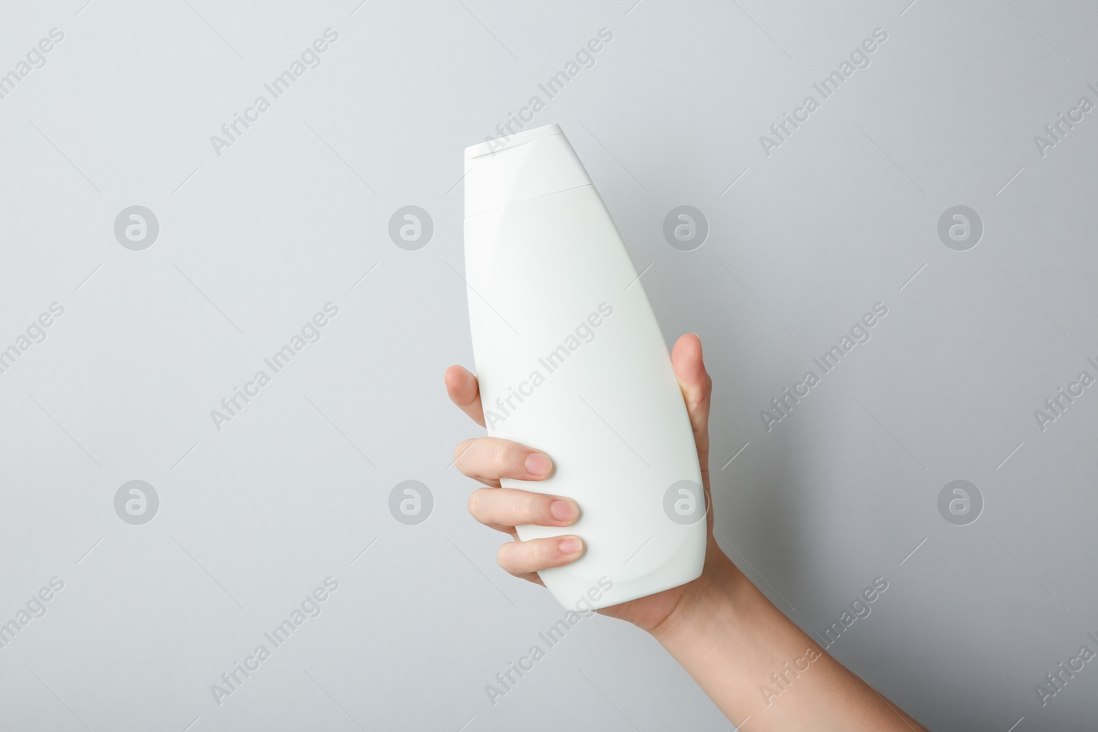 Photo of Woman with shampoo bottle on grey background, closeup