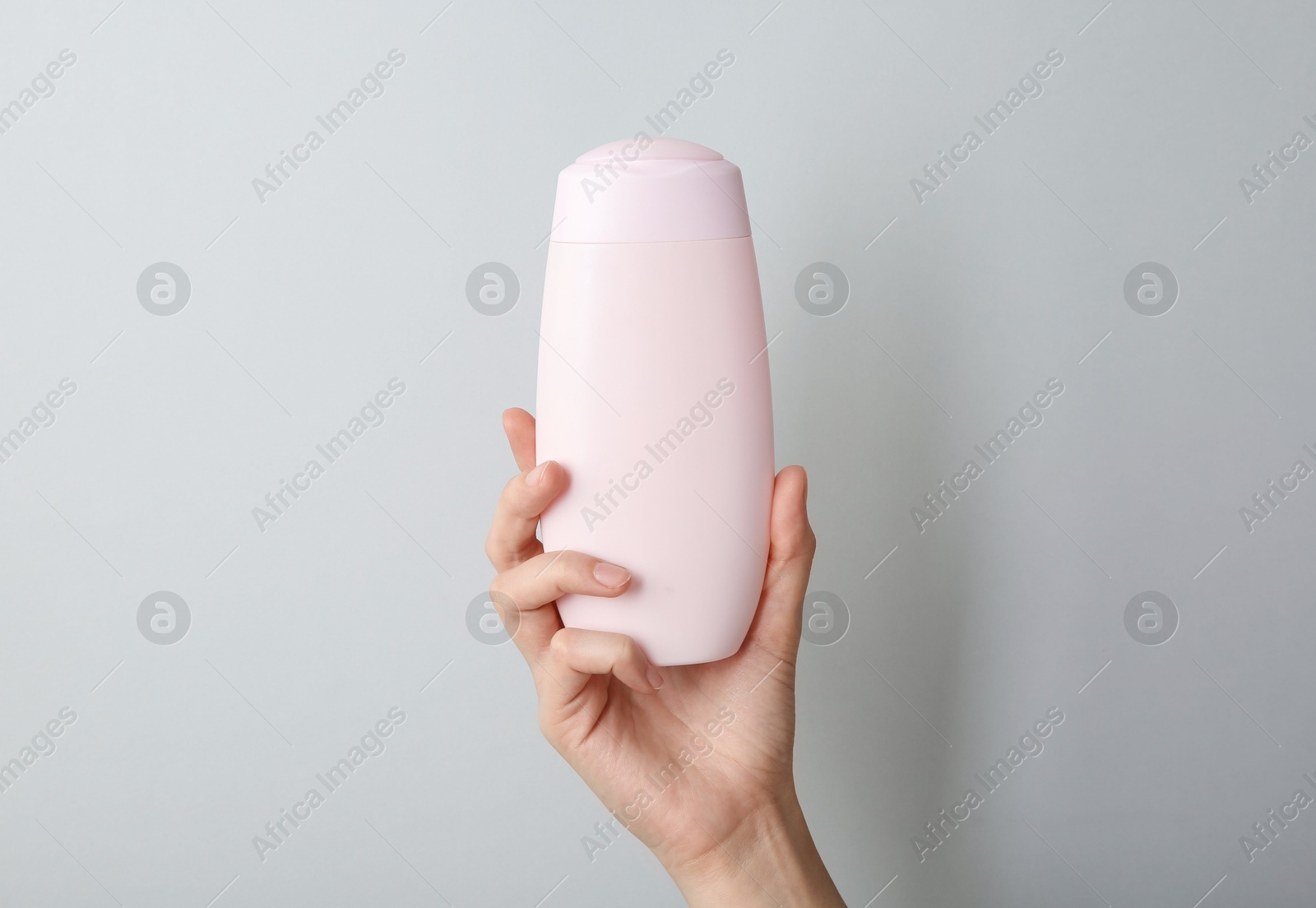 Photo of Woman with shampoo bottle on grey background, closeup