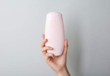 Photo of Woman with shampoo bottle on grey background, closeup