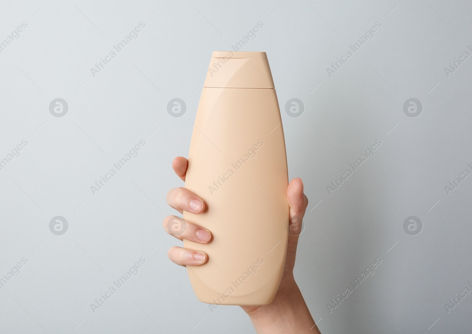 Photo of Woman with shampoo bottle on grey background, closeup