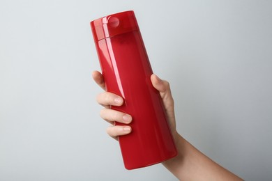 Photo of Woman with shampoo bottle on grey background, closeup