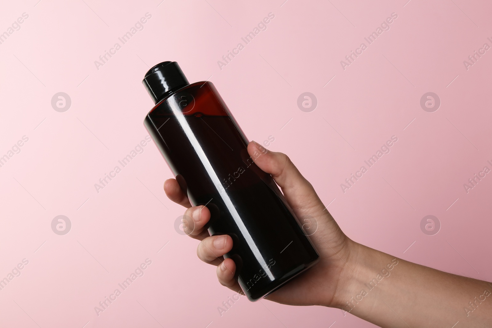 Photo of Woman with shampoo bottle on pink background, closeup