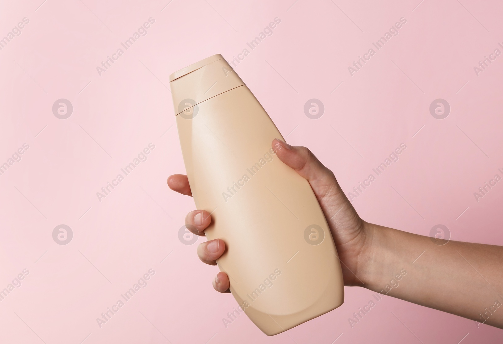 Photo of Woman with shampoo bottle on pink background, closeup