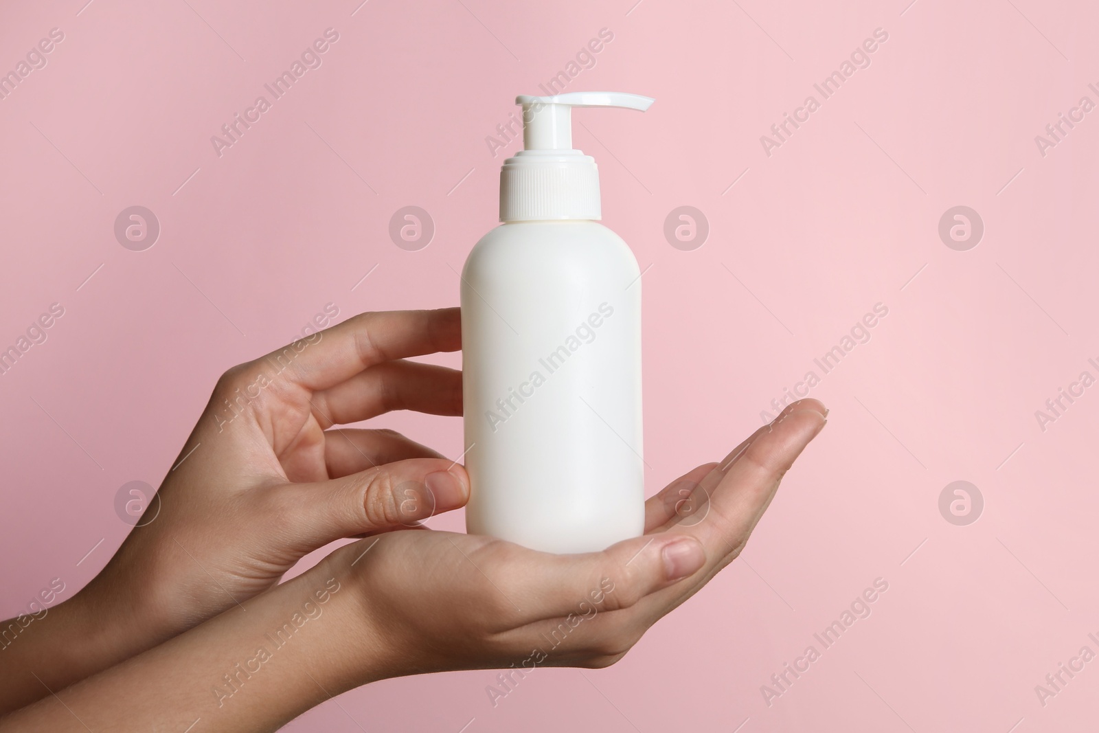 Photo of Woman with shampoo bottle on pink background, closeup