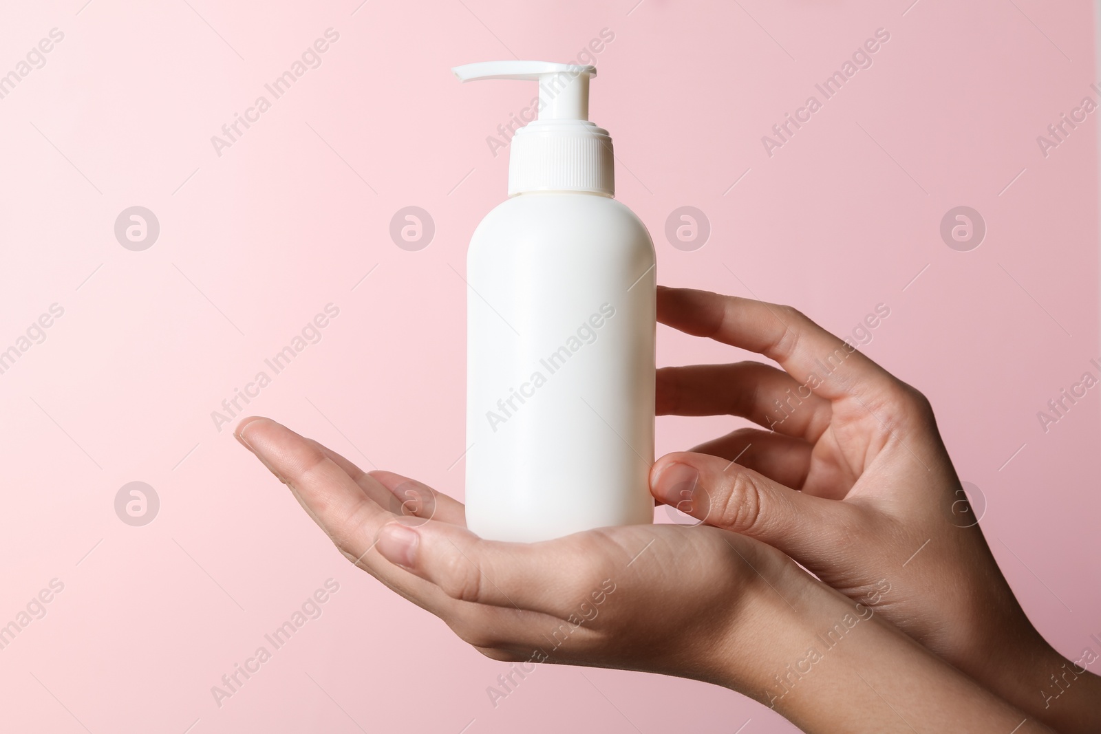 Photo of Woman with shampoo bottle on pink background, closeup