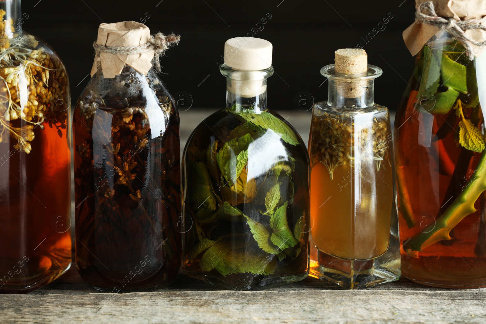 Photo of Different tinctures in bottles on wooden table, closeup