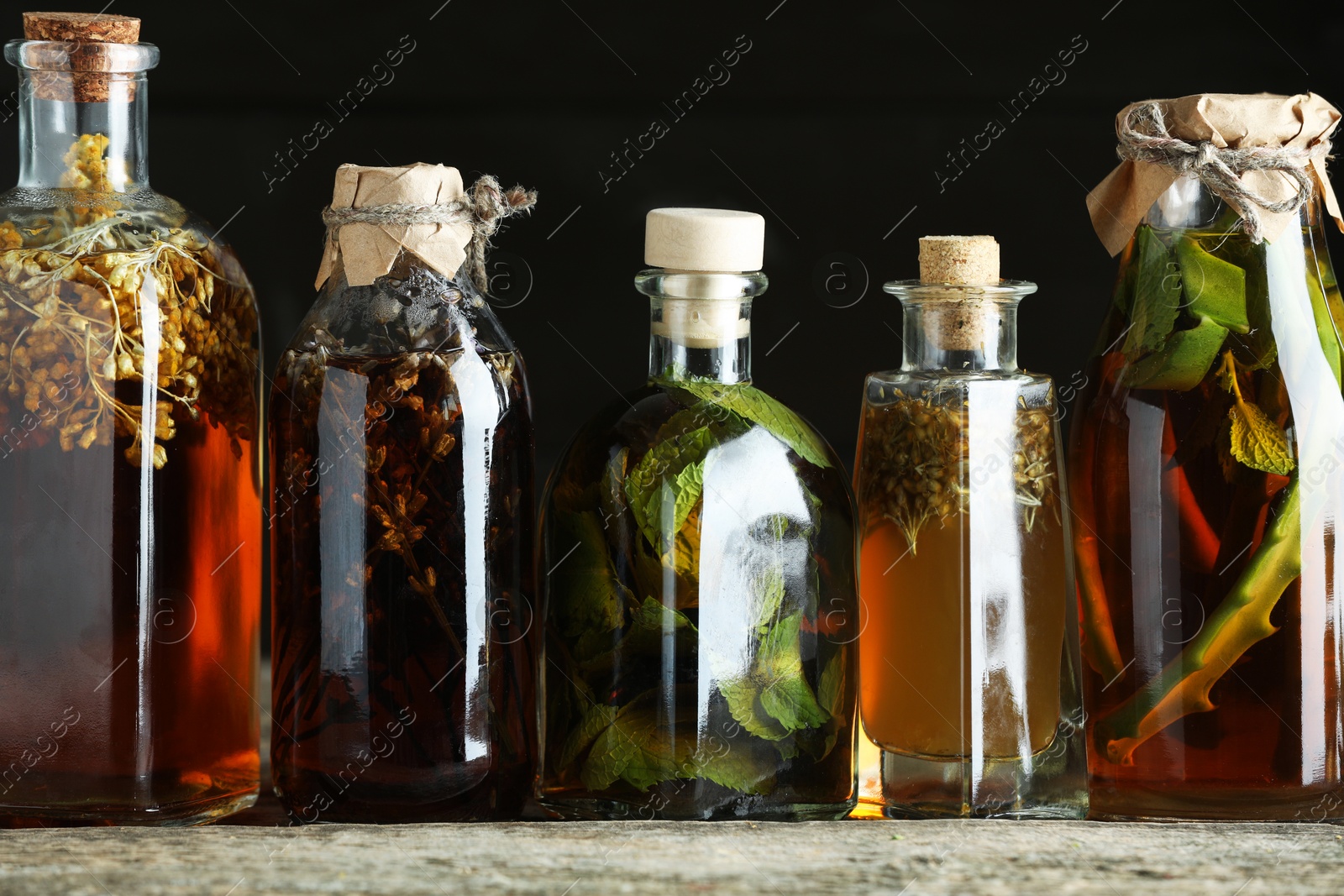 Photo of Different tinctures in bottles on wooden table, closeup