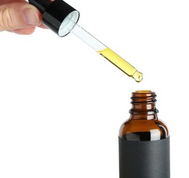 Photo of Woman dripping tincture from pipette into bottle against white background, closeup