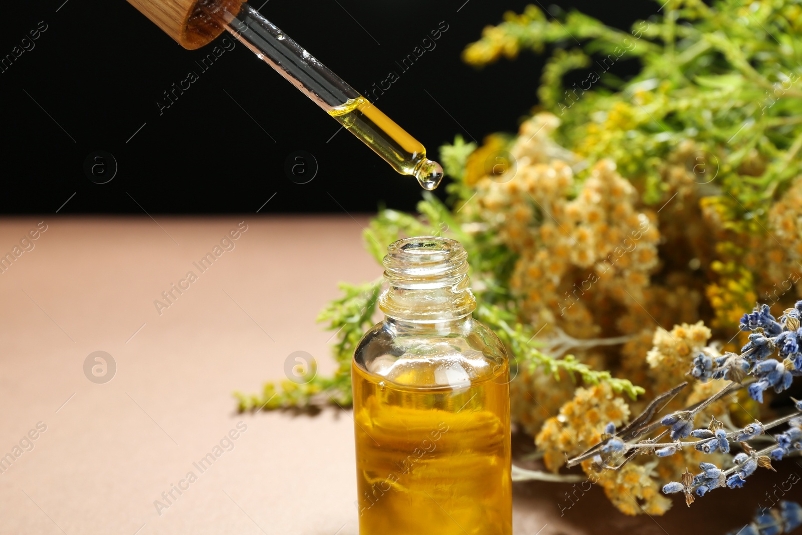 Photo of Dripping tincture from pipette into bottle and herbs against color background, closeup