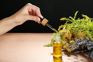 Photo of Woman dripping tincture from pipette into bottle and herbs against color background, closeup