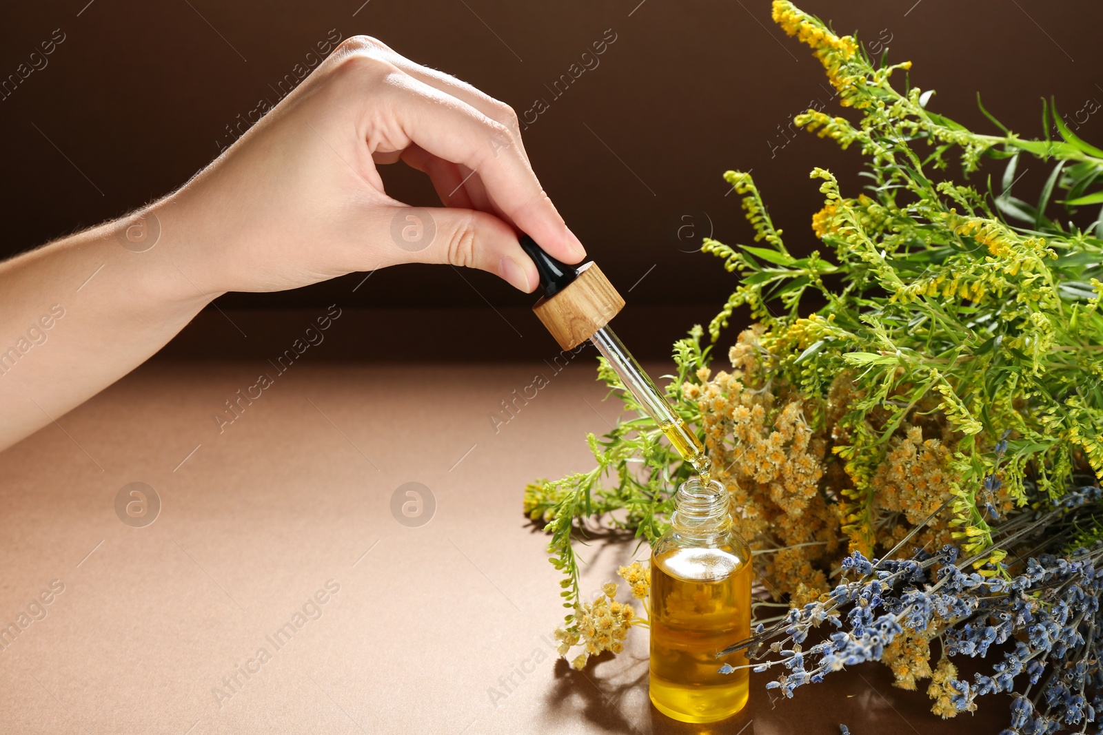 Photo of Woman dripping tincture from pipette into bottle and herbs on color background, closeup