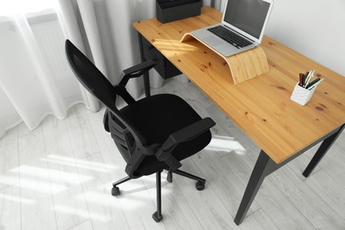 Photo of Black chair, laptop and desk in office, above view