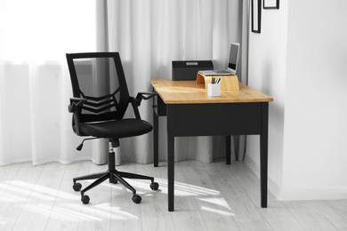 Photo of Black chair, laptop and desk in office