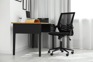 Black chair, laptop and desk in office