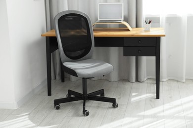 Photo of Grey chair, laptop and desk in office