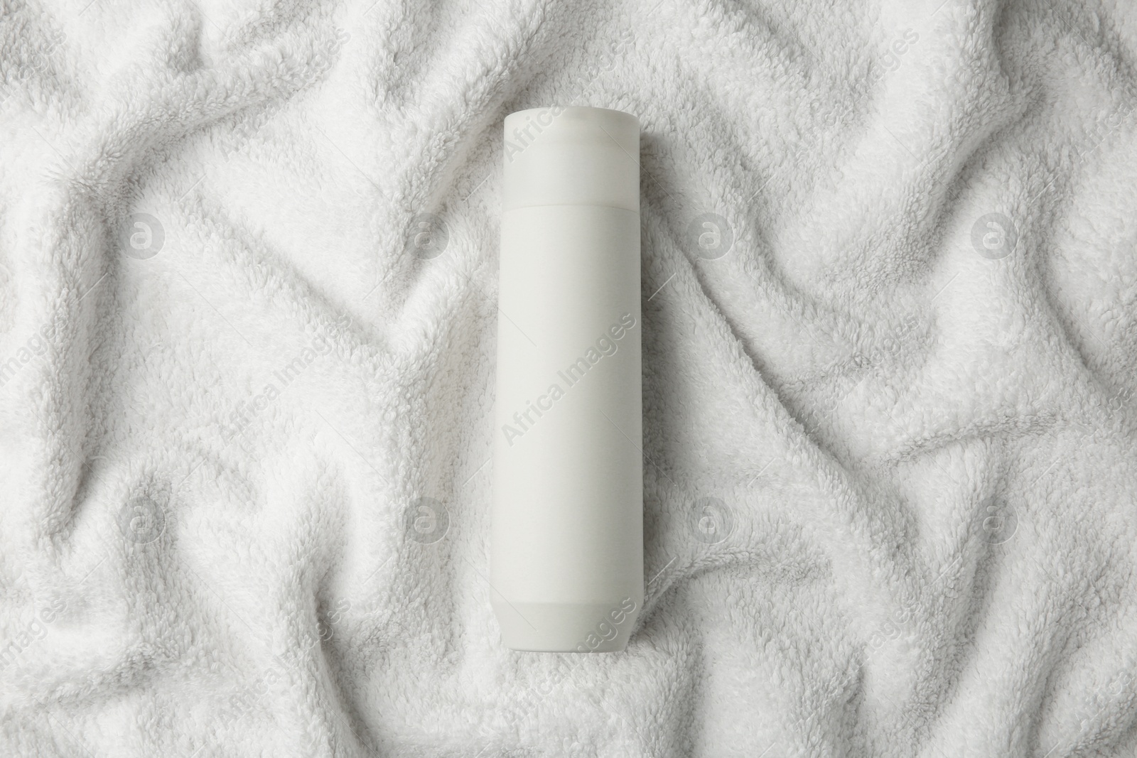 Photo of Bottle of shampoo on soft terry towel, top view