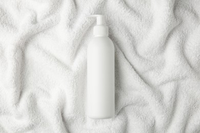 Photo of Bottle of shampoo on soft terry towel, top view