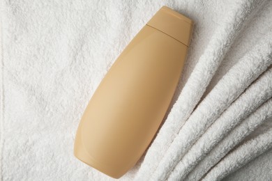 Photo of Bottle of shampoo on soft terry towel, top view