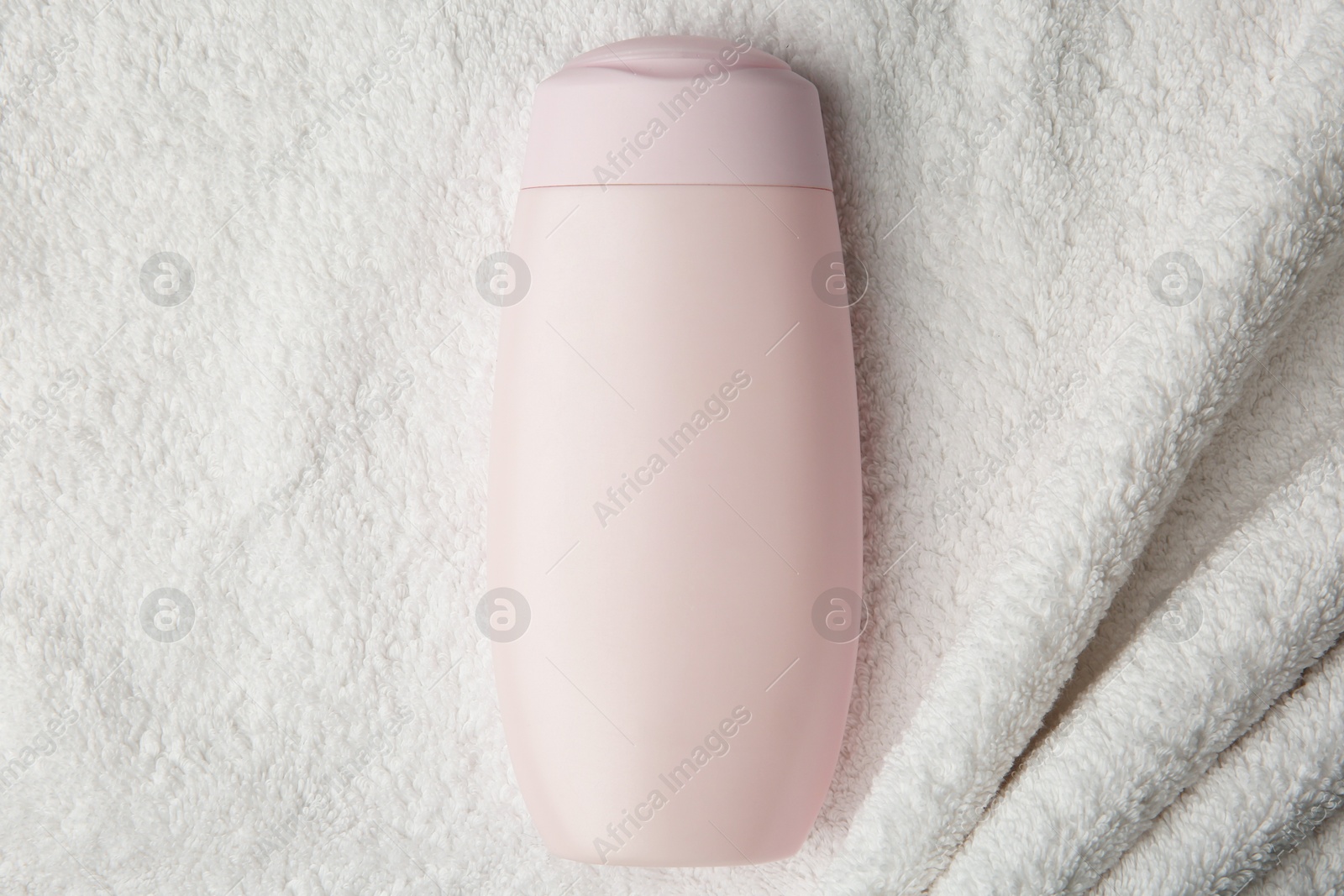 Photo of Bottle of shampoo on soft terry towel, top view