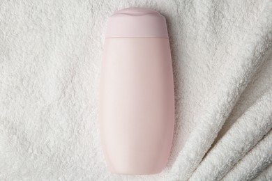 Photo of Bottle of shampoo on soft terry towel, top view