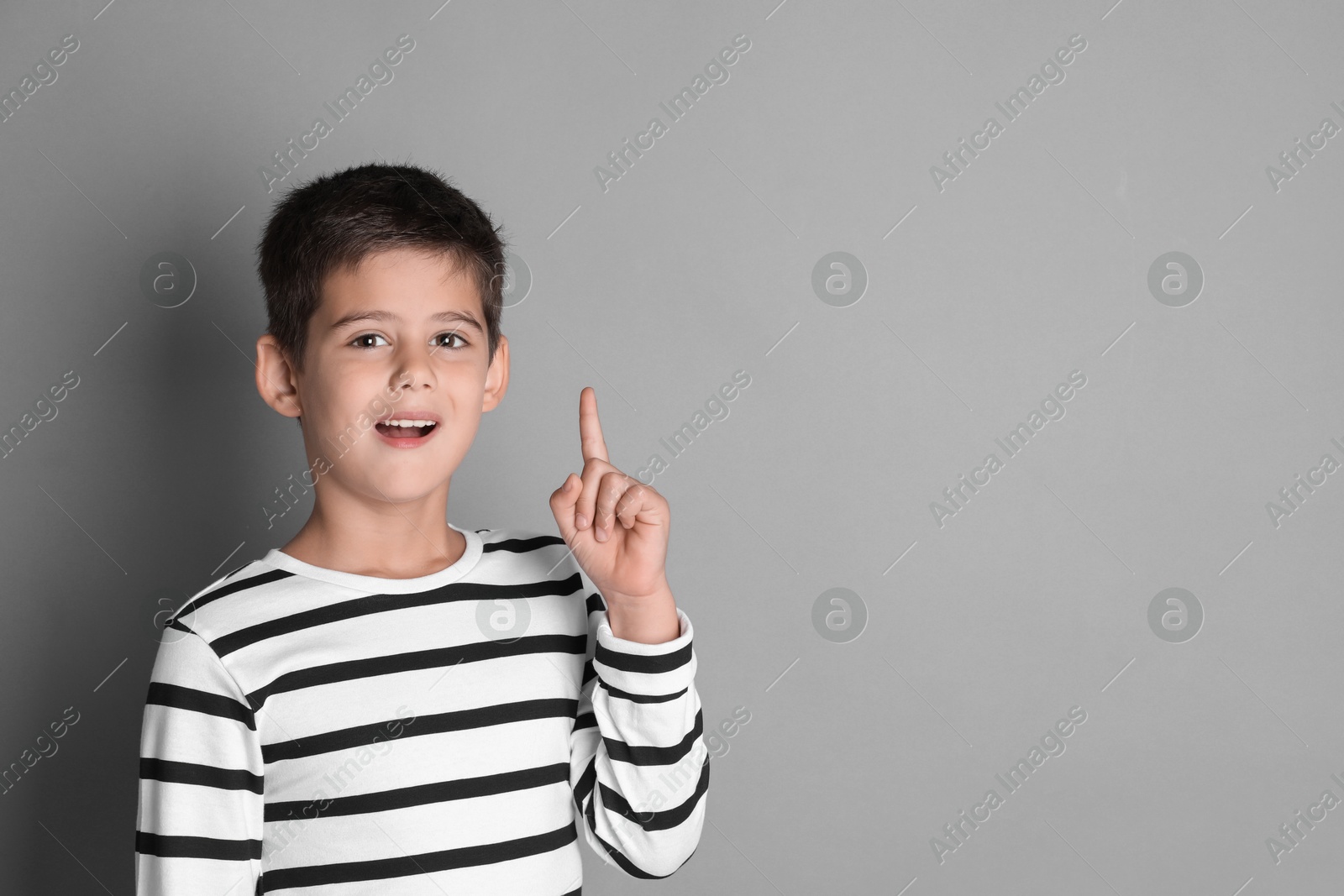 Photo of Portrait of cute little boy on grey background, space for text