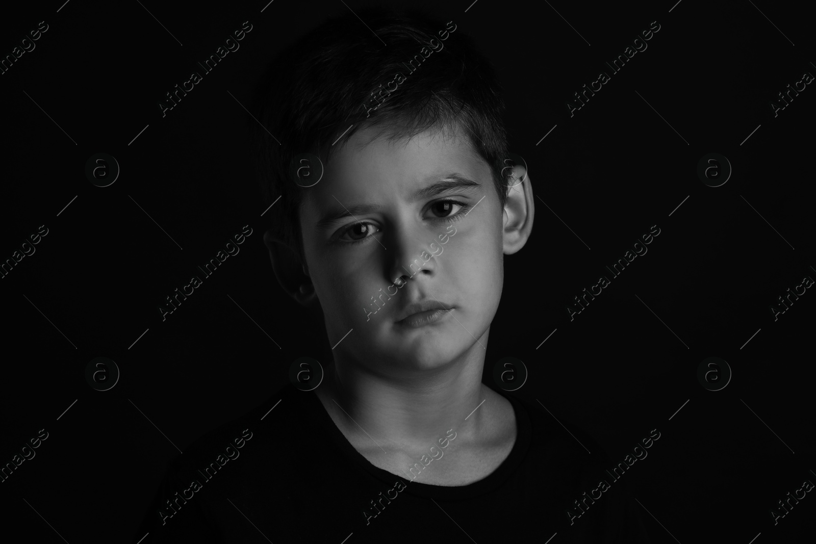 Photo of Portrait of sad little boy on dark background. Black and white effect