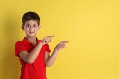 Photo of Portrait of cute little boy on yellow background, space for text