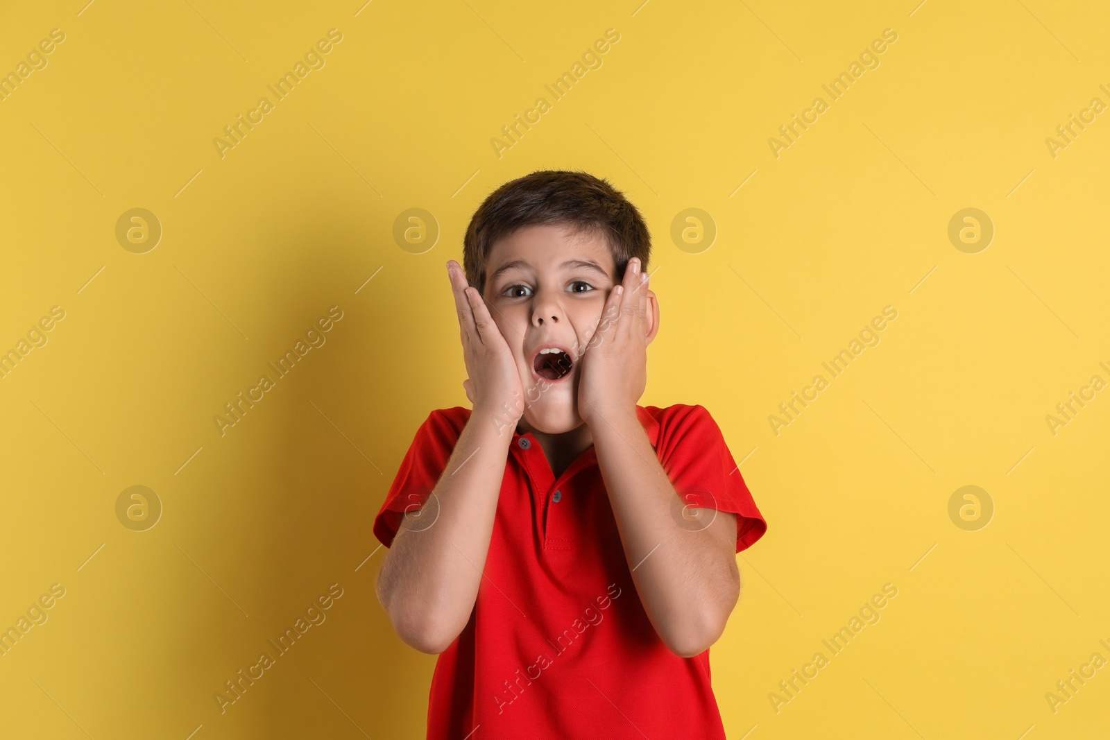 Photo of Portrait of emotional little boy on yellow background