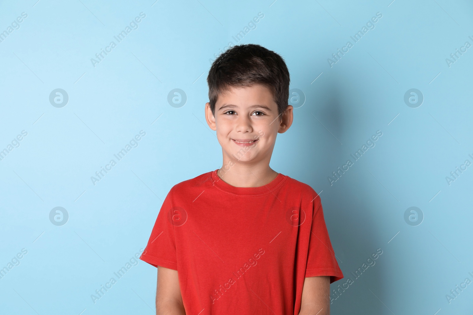 Photo of Portrait of cute little boy on light blue background