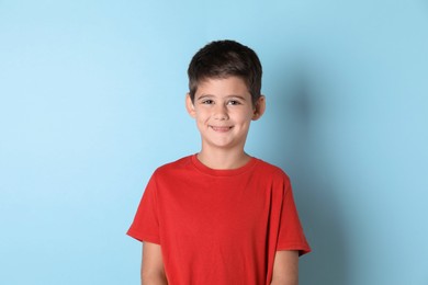 Portrait of cute little boy on light blue background