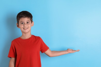 Photo of Portrait of cute little boy on light blue background