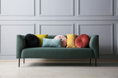 Photo of Stylish sofa with different cushions near grey wall