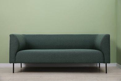 Photo of One stylish sofa near green wall indoors