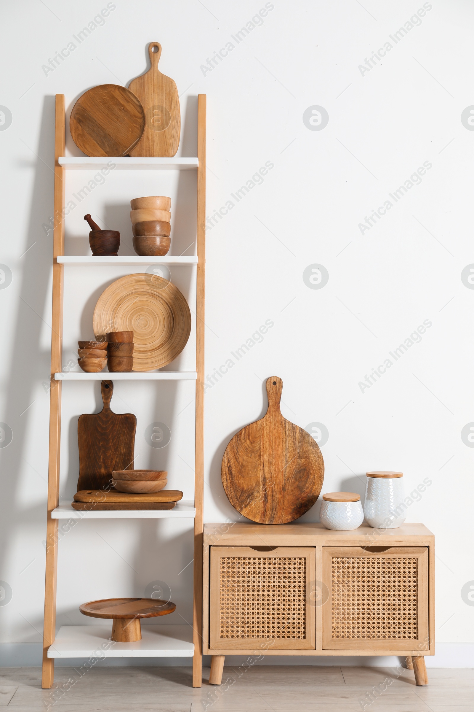 Photo of Storage stand and cabinet with kitchenware near white wall indoors