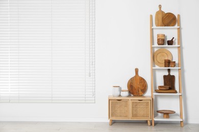 Storage stand and cabinet with kitchenware near white wall indoors