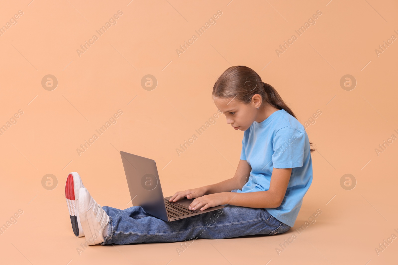 Photo of Girl with incorrect posture and laptop sitting on beige background