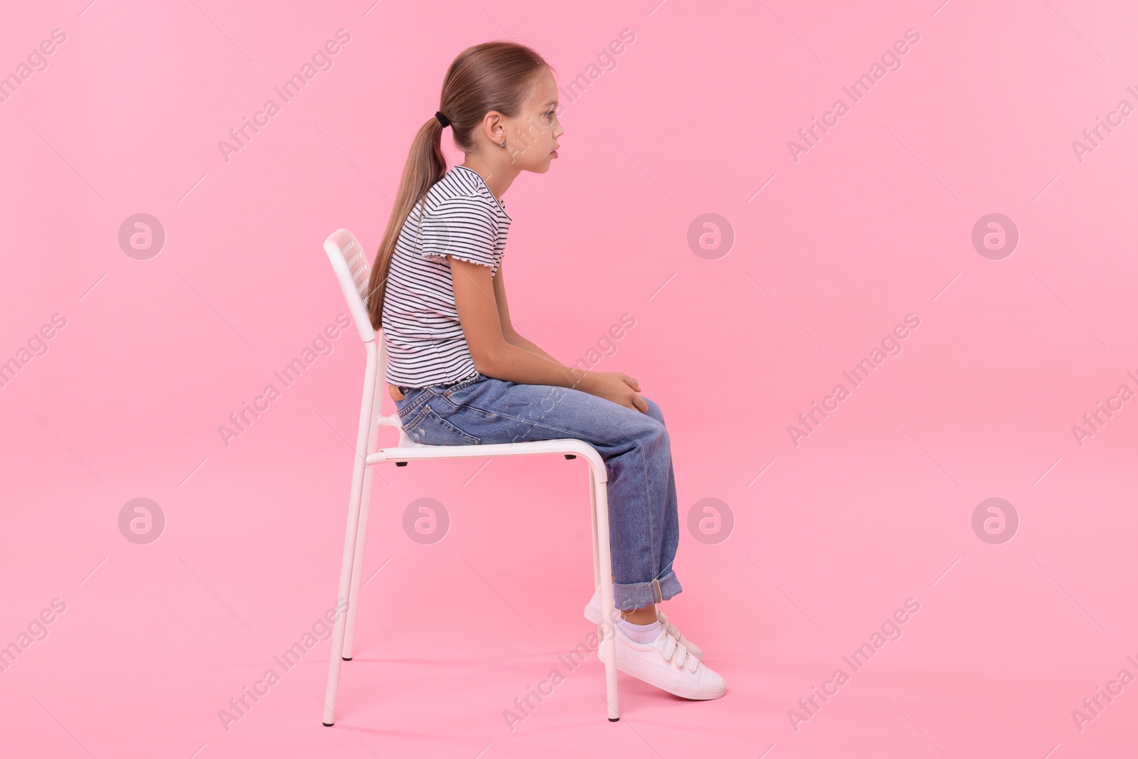 Photo of Girl with incorrect posture sitting on chair against pink background