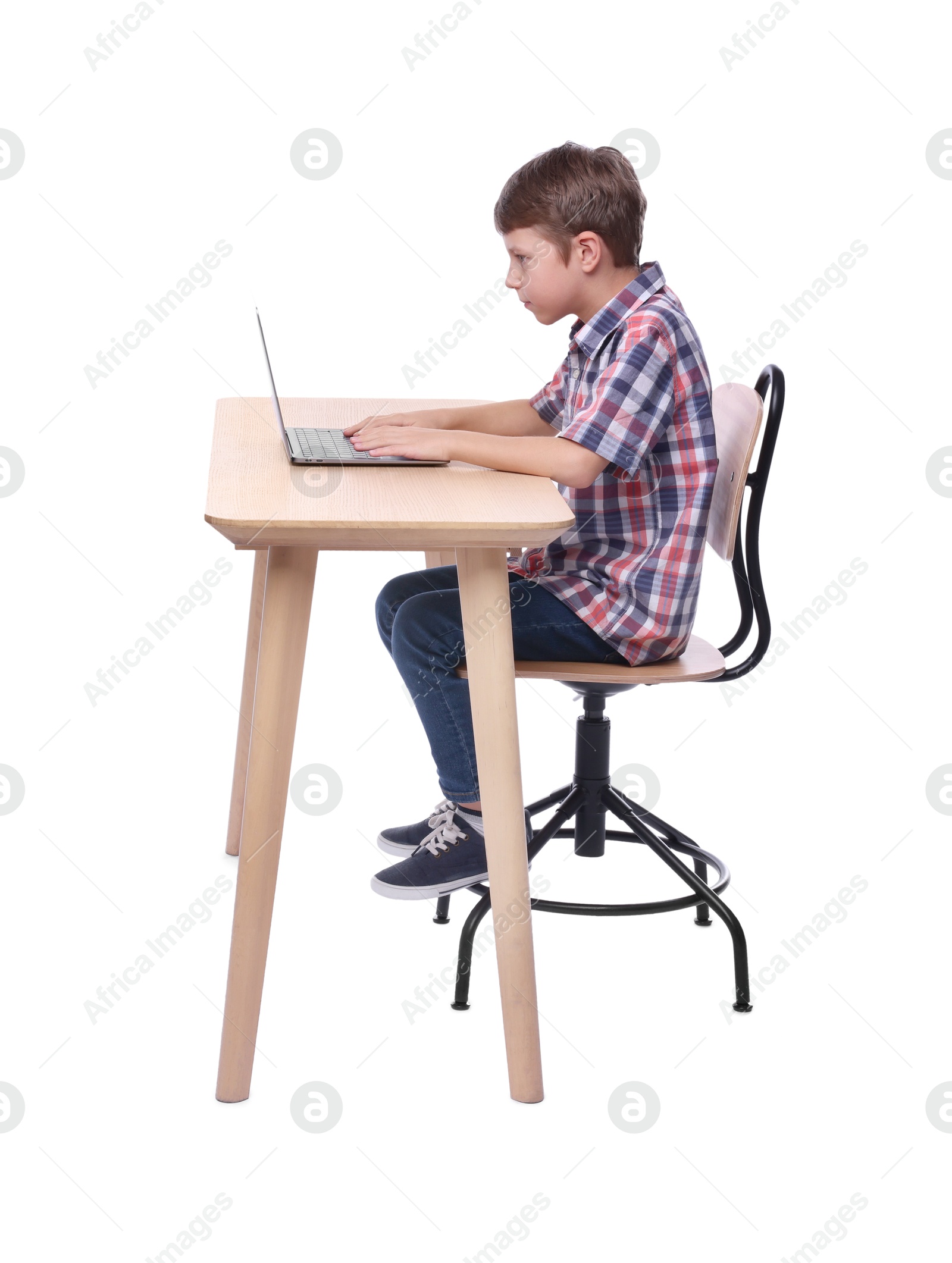 Photo of Boy with incorrect posture using laptop at wooden desk on white background