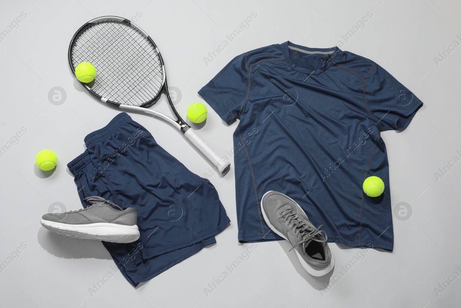 Photo of Tennis racket, balls and sportswear on light background, flat lay