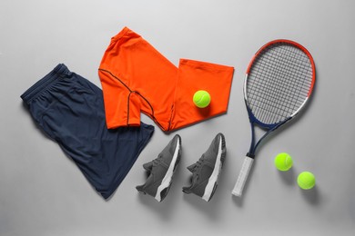 Photo of Tennis racket, balls, sneakers and sportswear on grey background, flat lay