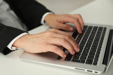 Photo of Businesswoman using laptop at white table indoors, closeup. Modern technology