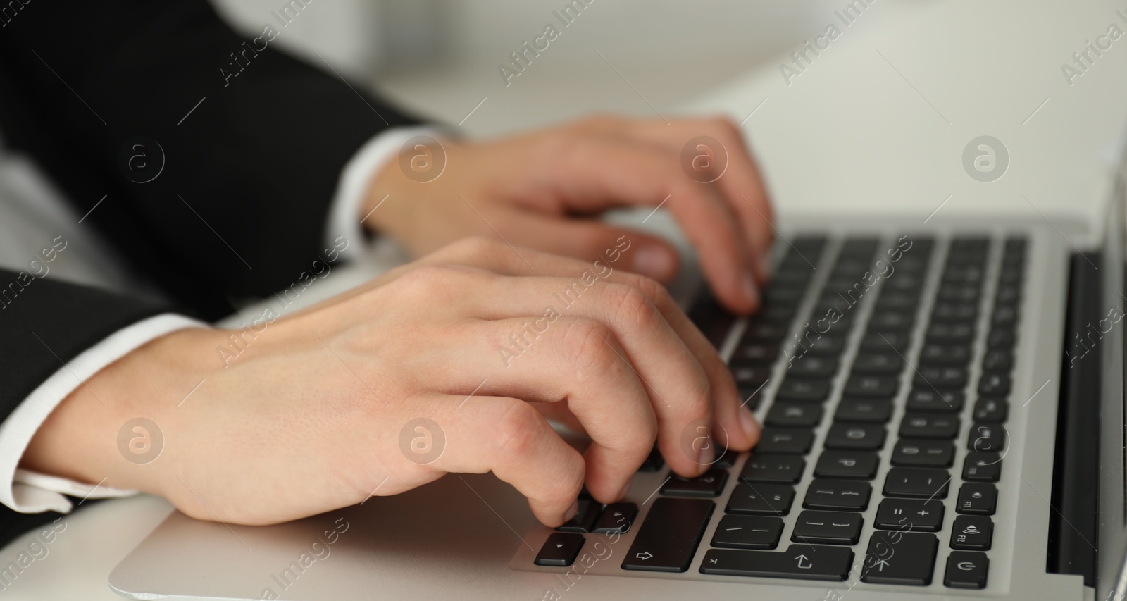 Photo of Businesswoman using laptop at white table indoors, closeup. Modern technology