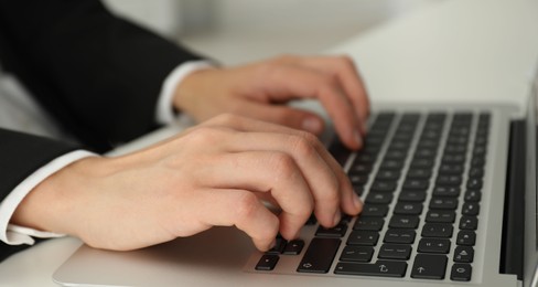 Photo of Businesswoman using laptop at white table indoors, closeup. Modern technology