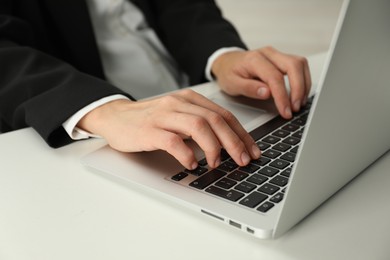 Photo of Businesswoman using laptop at white table indoors, closeup. Modern technology