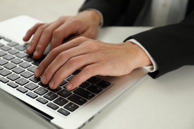 Photo of Businesswoman using laptop at white table indoors, closeup. Modern technology