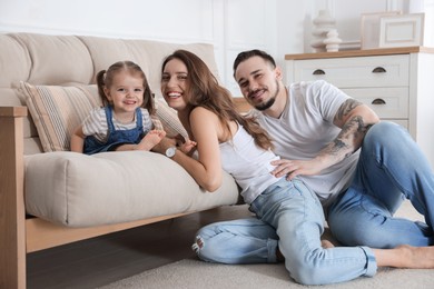 Photo of Happy family. Parents and their cute little daughter on sofa at home