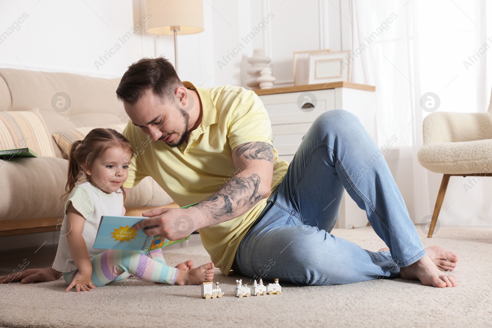 Photo of Happy family. Father and his cute little daughter reading book at home